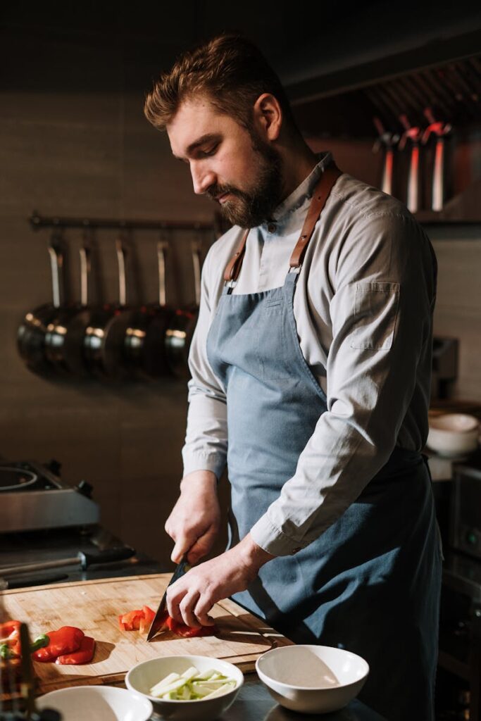 Chef slicing vegetables in a modern kitchen setting, showcasing culinary skills.